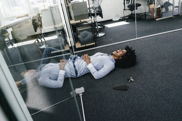 Junge Frau auf dem Boden liegend im Büro - KNSF02280