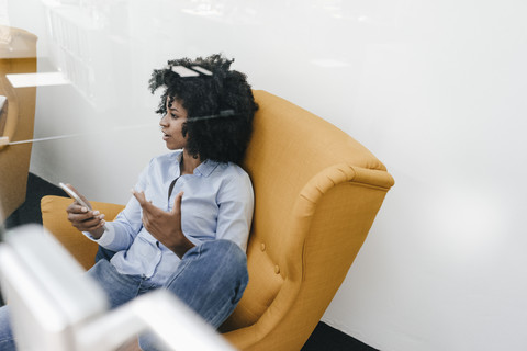 Young woman with cell phone sitting in armchair stock photo