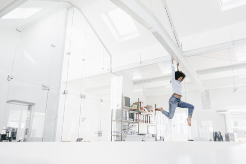 Young woman hanging on beam in office - KNSF02284