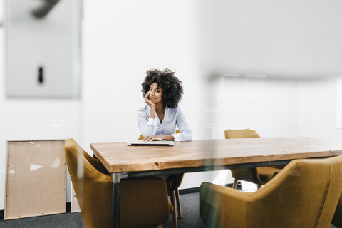 Portrait of young woman sitting at table in office stock photo