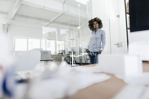 Junge Frau im Büro stehend, lizenzfreies Stockfoto