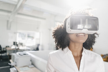 Woman wearing VR glasses in office - KNSF02305