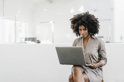 Young woman using laptop in office - KNSF02312