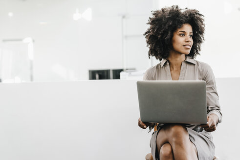 Young woman using laptop in office - KNSF02313