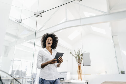 Happy young woman in office holding tablet - KNSF02324