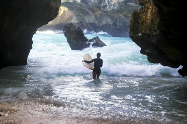 Indonesien, Bali, Rückenansicht eines Surfers mit Surfbrett - KNTF00868