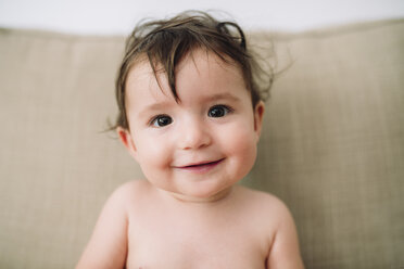 Portrait of smiling baby girl sitting on couch - GEMF01750