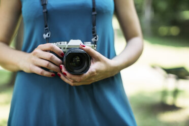 Woman's hands holding analogue camera, close-up - MOMF00220