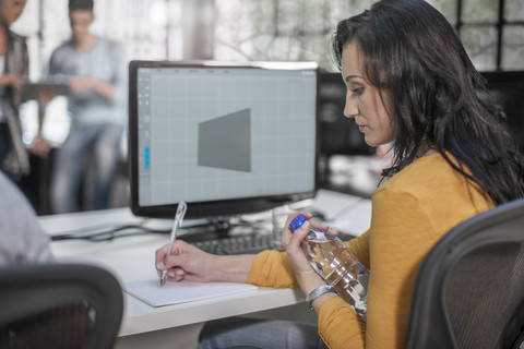 Erwachsenenbildung, Frau macht Notizen im Computerschulungszentrum, lizenzfreies Stockfoto