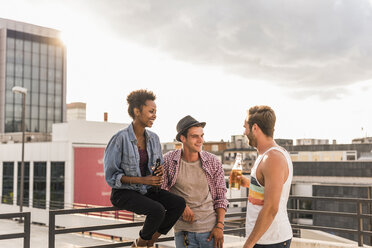 Drei Freunde beim geselligen Beisammensein auf einer Dachterrassenparty - UUF11473