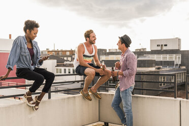 Drei Freunde beim geselligen Beisammensein auf einer Dachterrassenparty - UUF11474