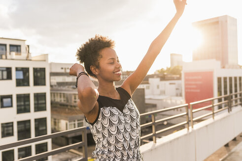 Happy young woman moving on rooftop - UUF11495