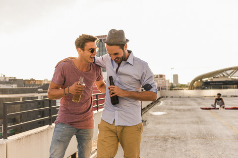 Zwei Freunde mit Bierflaschen auf einer Dachterrasse, lizenzfreies Stockfoto