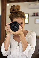 Portrait of laughing young woman taking picture with camera - ECPF00050