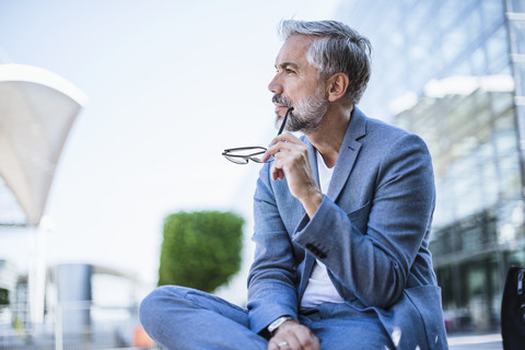 Businessman sitting outdoors thinking stock photo