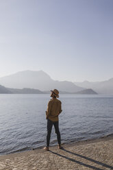 Italy, Lierna, man standing at lakeside promenade enjoying sunset - MRAF00216