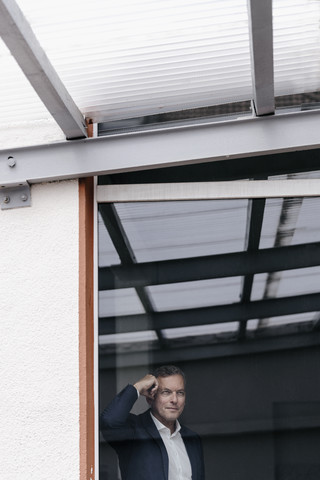 Geschäftsmann schaut aus dem Fenster, lizenzfreies Stockfoto