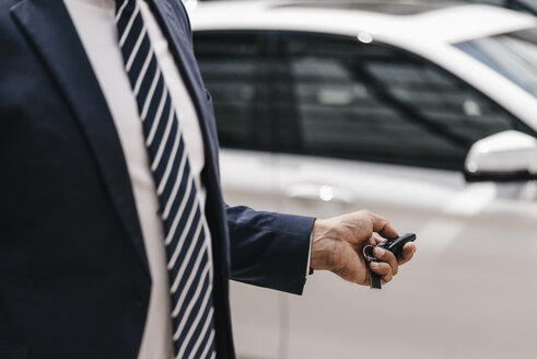 Businessman using remote control key of car, partial view - KNSF02391