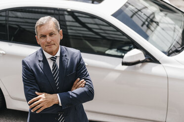 Portrait of mature businessman standing in front of car - KNSF02393