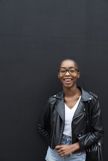 Portrait of laughing young woman wearing black leather jacket - IGGF00097