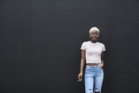 Portrait of young woman with cigarette in front of black background stock photo