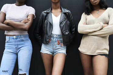 Three friends standing side by side against black background, partial view - IGGF00102