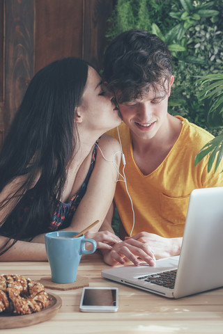 Young couple having coffee and chocolate braids using laptop at home stock photo