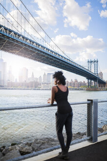 USA, New York City, Brooklyn, Frau hört Musik in der Nähe der Manhattan Bridge - GIOF03089