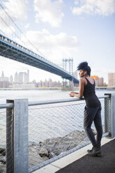USA, New York City, Brooklyn, Frau hört Musik in der Nähe der Manhattan Bridge - GIOF03090