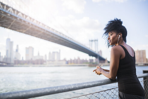 USA, New York City, Brooklyn, Frau hört Musik in der Nähe der Manhattan Bridge - GIOF03091