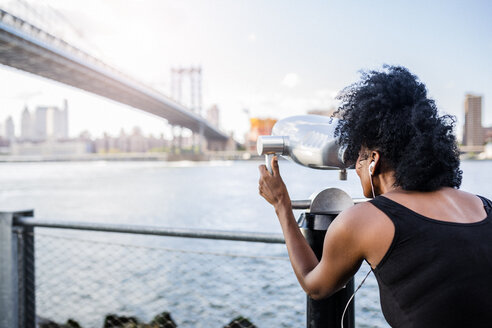 USA, New York City, Brooklyn, Frau schaut durch ein münzbetriebenes Fernglas auf die Manhattan Bridge - GIOF03092