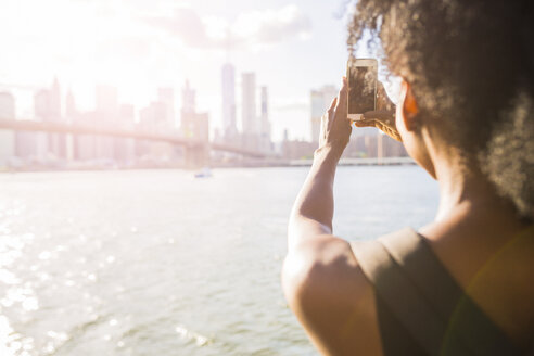 USA, New York City, Brooklyn, Frau nimmt Handy-Foto von Skyline - GIOF03095