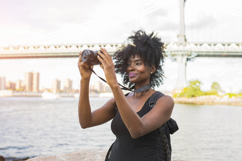 USA, New York City, Brooklyn, Frau schaut in die Kamera am Wasser, lizenzfreies Stockfoto