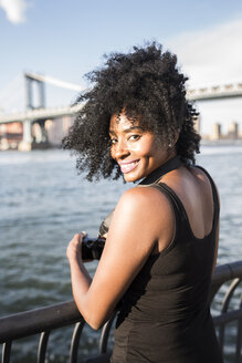USA, New York City, Brooklyn, Porträt einer lächelnden Frau, die am Wasser steht - GIOF03113