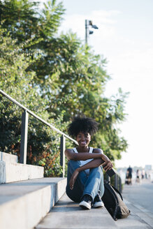 Porträt einer lächelnden Frau, die auf einer Treppe im Freien sitzt - GIOF03132