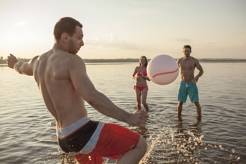 Glückliche Freunde spielen mit einem Ball im Wasser, lizenzfreies Stockfoto