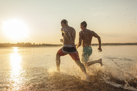 Two friends running in water stock photo