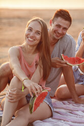 Glückliches Paar mit Freunden am Strand, die Wassermelone essen - VPIF00021