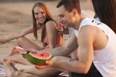 Glückliches Paar mit Freunden am Strand, die Wassermelone essen - VPIF00022