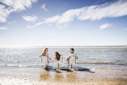Niederlande, Zandvoort, Familie sitzt auf Stühlen im Meer - FMKF04318