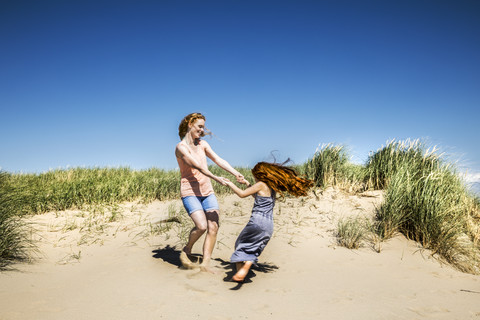 Niederlande, Zandvoort, glückliche Mutter und Tochter tanzen in den Stranddünen, lizenzfreies Stockfoto