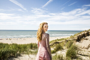 Niederlande, Zandvoort, Porträt einer lächelnden Frau, die in den Dünen steht - FMKF04356