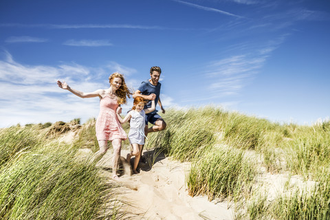 Niederlande, Zandvoort, glückliche Familie mit Tochter läuft in den Stranddünen, lizenzfreies Stockfoto