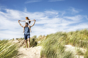 Netherlands, Zandvoort, father carrying daughter on shoulders in beach dunes - FMKF04363