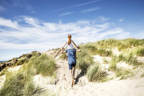 Netherlands, Zandvoort, father carrying daughter on shoulders in beach dunes stock photo