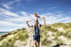 Netherlands, Zandvoort, father carrying daughter on shoulders in beach dunes - FMKF04366