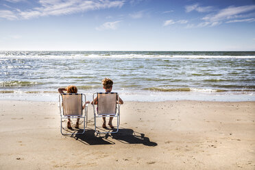 Netherlands, Zandvoort, boy and girl sitting on chairs on the beach - FMKF04369