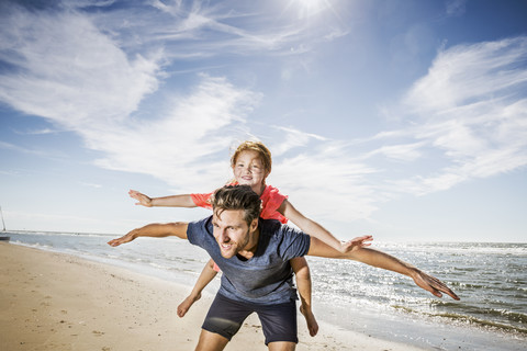 Niederlande, Zandvoort, Vater trägt Tochter am Strand, lizenzfreies Stockfoto