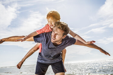 Netherlands, Zandvoort, father carrying daughter on the beach - FMKF04371