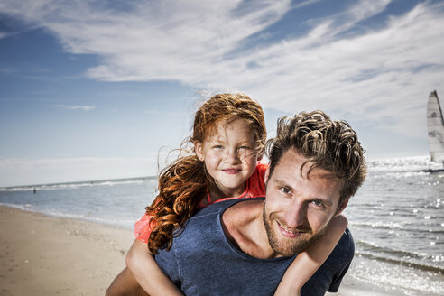Niederlande, Zandvoort, Porträt eines lächelnden Vaters mit Tochter am Strand - FMKF04372